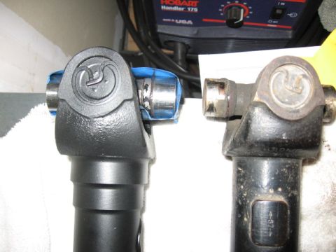 1995 Ford Bronco - Comparison of a new driveshaft U-joint with an older, worn one. A welder is visible in the background.