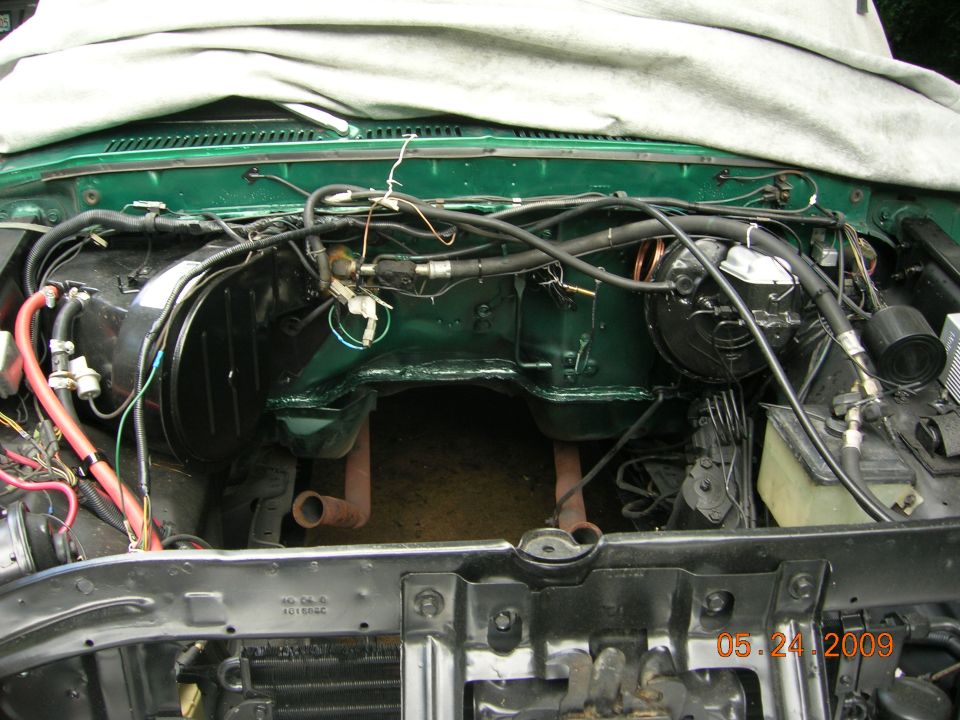 Engine bay of a green truck stripped during a repaint and rewire