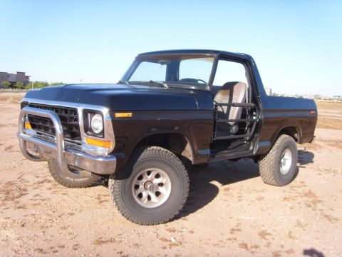 1978 Ford Bronco - A black 1978 Ford Bronco sits in a dirt lot under a clear blue sky.