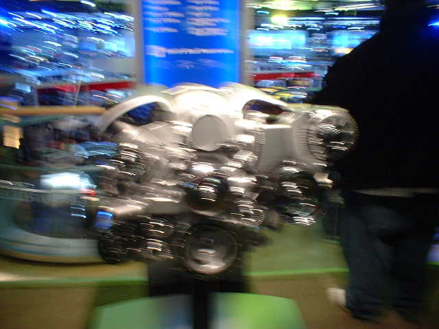 Engine on display stand, blurry background with blue signage