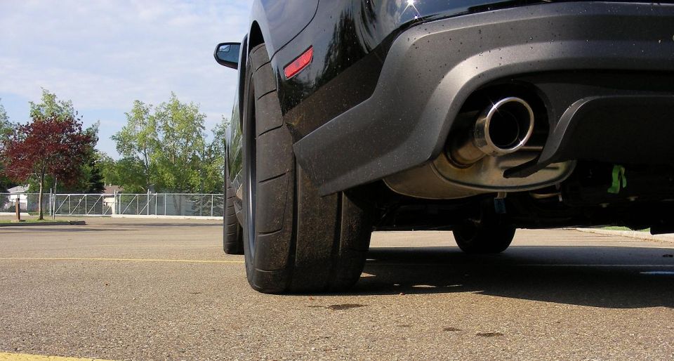 Black 2011 Ford Mustang rear tire and exhaust pipe, low angle view