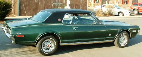 1968 Mercury Cougar - A green 1968 Mercury Cougar coupe with a black vinyl roof is parked outdoors, with other vehicles in the background.