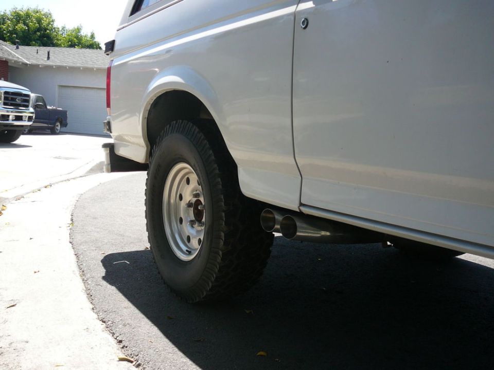 Side view of a white 1988 Ford Bronco with dual exhaust pipes