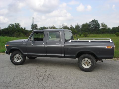 1979 Ford F-250 - This 1979 Ford F-250 pickup truck is shown from the side, parked on a paved road with trees in the background.