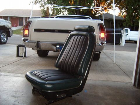 1973 Ford Ranchero - A detached car seat sits in front of a white pickup truck, with another white truck visible in the background.