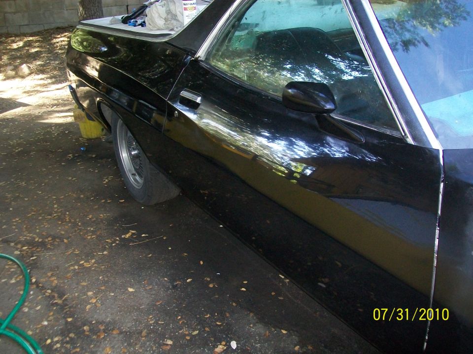 Black 1972 Ford Ranchero side view, showing a dented rear fender and roll-on paint