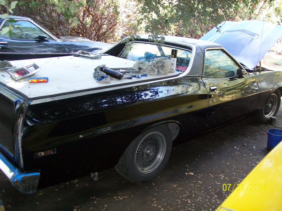 Black 1972 Ford Ranchero with hood open and parts on the bed cover