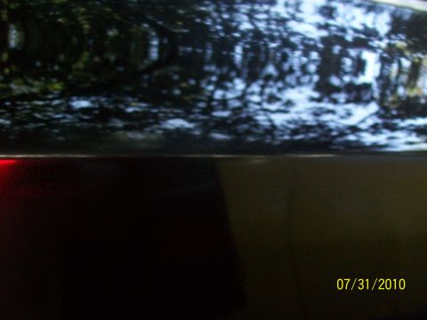 1972 Ford Ranchero - Reflections on the dark paint of a vehicle's side, with a visible red taillight and a date stamp.