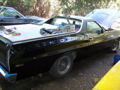 1972 Ford Ranchero - A black 1972 Ford Ranchero is parked outside with its hood up and tools on the bed cover.