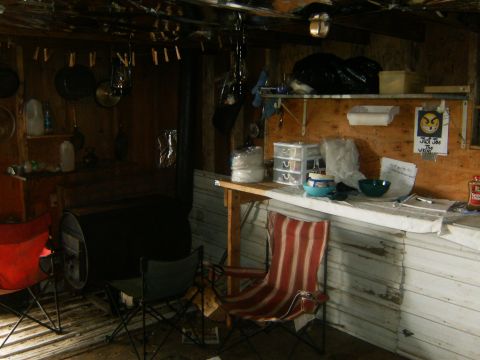 2000 Ford E350 - Interior view of a rustic cabin, camping chairs, a counter with bowls, and a large barrel. The registry claims it is a 2000 Ford E350, but…