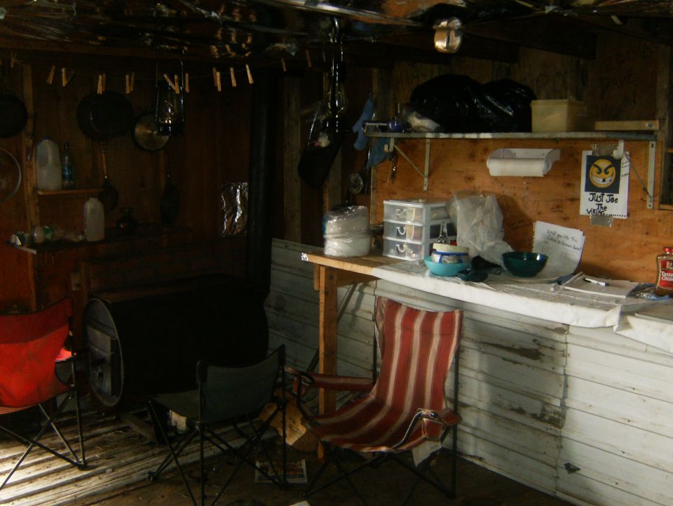 Interior of a rustic cabin with chairs, counter, and a large barrel