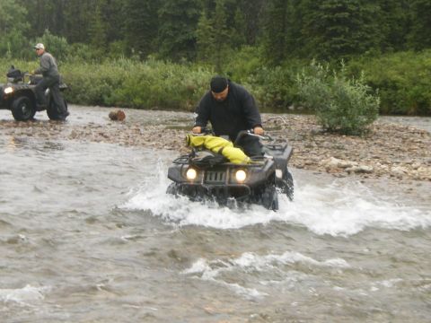 2000 Ford E350 - Two ATVs navigate a shallow river, kicking up water as they go.