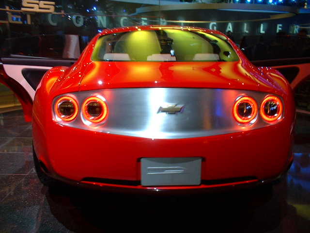 Rear view of a red concept car with four circular taillights and a silver panel with a Chevrolet logo