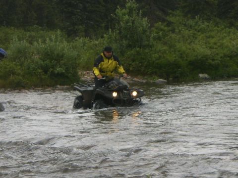 2000 Ford E350 - An all-terrain vehicle navigates through a river with a rider wearing a yellow jacket.