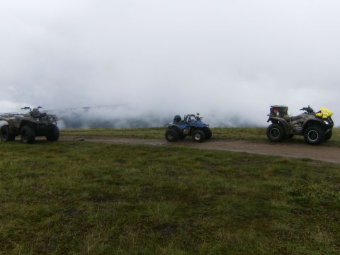 2000 Ford E350 - Three ATVs are parked on a dirt road with a foggy, mountainous landscape in the background.