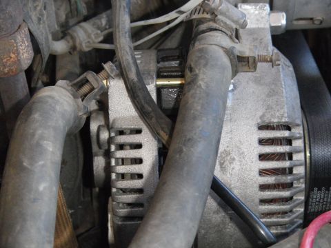 1991 Ford Bronco - Close-up view of an alternator and associated hoses within an engine compartment.