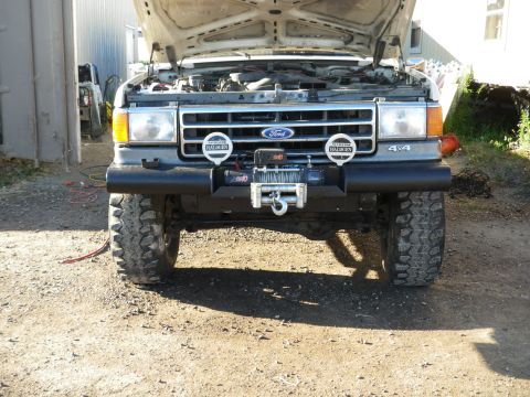 1991 Ford Bronco - This Ford Bronco features a winch and off-road tires, with its hood open revealing the engine compartment.