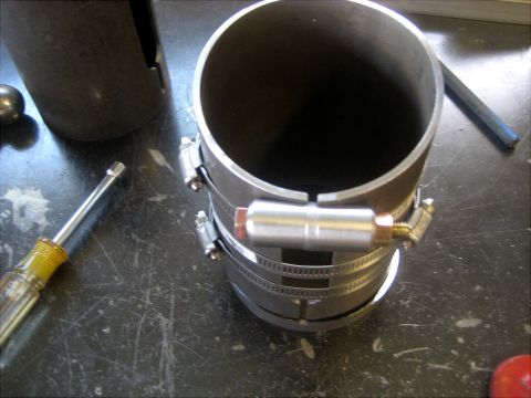 1996 Ford Bronco - Close-up of a metal pipe assembly with hose clamps and a sensor, on a workbench.