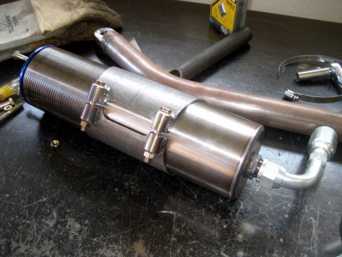 1996 Ford Bronco - A shock absorber sits on a workbench next to various metal parts and tools.