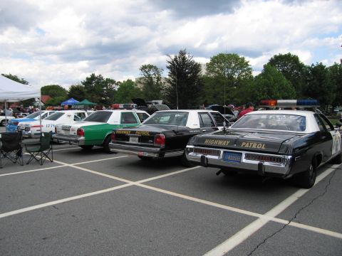 1991 Ford LTD Crown Victoria - Several marked patrol cars seen from the rear, including black-and-white HIGHWAY PATROL units and a green-and-white car, parked at a show.