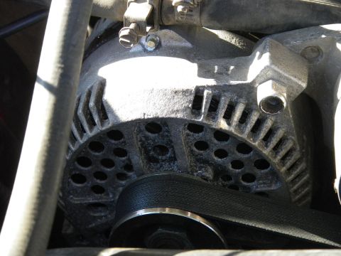 1991 Ford Bronco - Close-up view of an alternator with its drive belt engaged.