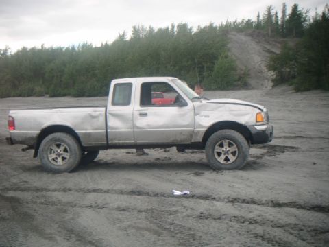 1993 Suzuki Sidekick - A silver pickup truck sits in a dirt lot with visible damage to its front end.