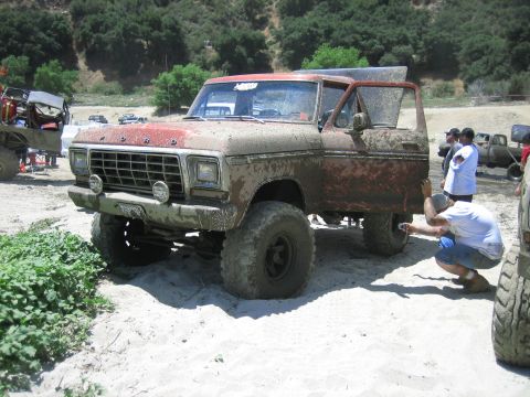 1986 Ford Bronco - Muddy 1978 Ford Bronco at an off-road event with multiple vehicles present.