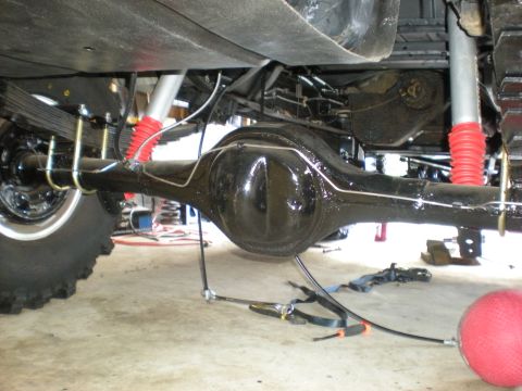 1978 Ford Bronco - Close-up of rear axle and suspension components, with tools visible on the garage floor.