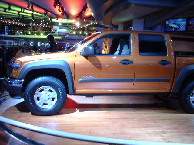 Orange pickup truck, side view, at an auto show