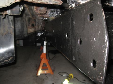 1979 Ford Bronco - Vehicle frame rail being worked on, supported by jack stands in a garage.