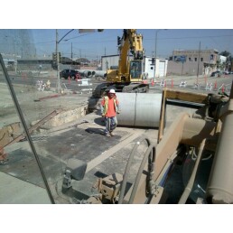 1988 Ford Bronco - A construction site is shown with heavy machinery and a worker near a large concrete pipe.