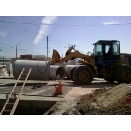 1988 Ford Bronco - Construction equipment is used to move large concrete pipes at a job site.