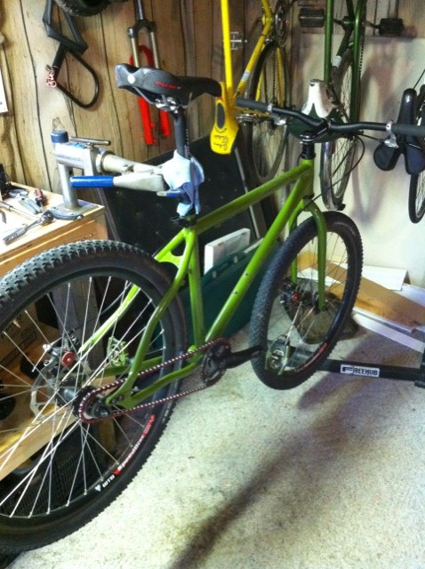 2010 Hyundai Genesis - A green bicycle is mounted on a repair stand in a workshop setting, with other bicycles visible in the background.