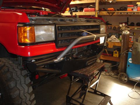 1989 Ford Bronco - Front view of a red Ford truck with a custom bumper installed in a workshop.