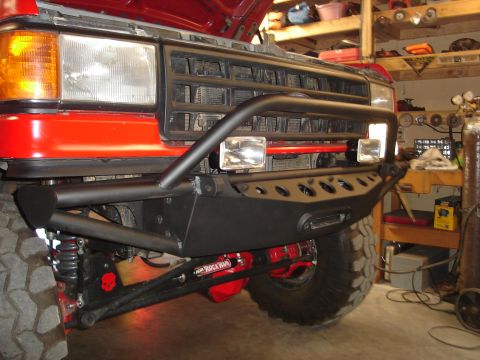 1989 Ford Bronco - Front view of a red Ford Bronco with a modified bumper and off-road tires.