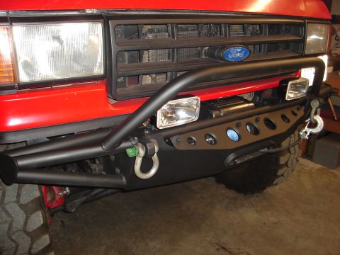 1989 Ford Bronco - Close-up of a red Ford Bronco's front bumper and grille, showing custom modifications.