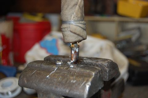 1994 Ford Bronco - Close-up of a wire-wrapped, cloth-taped shift lever or rod clamped upright in the jaws of a bench vise, with fresh silver solder or braze b…