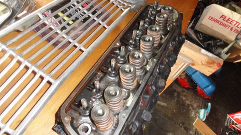 1964 Ford Fairlane - Close-up of an engine cylinder head with valve springs and retainers, alongside a chrome grille piece.