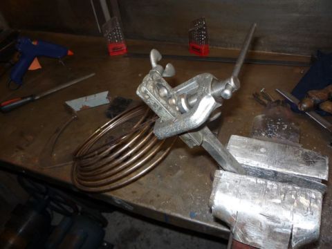 1969 MINI Cooper - A brake line flaring tool is used with coiled copper tubing on a workbench, with a hot glue gun and drill bits visible.