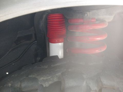 1991 Ford Bronco - Close-up view of a red coil spring and shock absorber assembly, a red bellows cover.