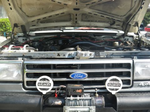 1991 Ford Bronco - Front view of a 1991 Ford Bronco with the hood open, revealing the engine and a winch installed.