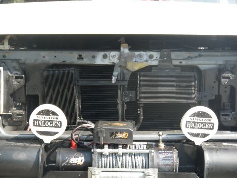 1991 Ford Bronco - The front grille and radiator of a white Ford Bronco are visible, equipped with a winch and auxiliary lights.