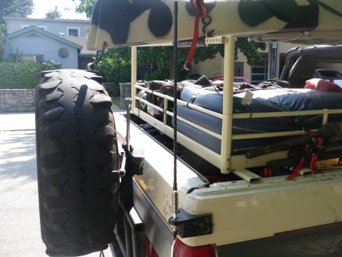 1991 Ford Bronco - Pickup truck bed configured for camping, with a spare tire and various gear secured.