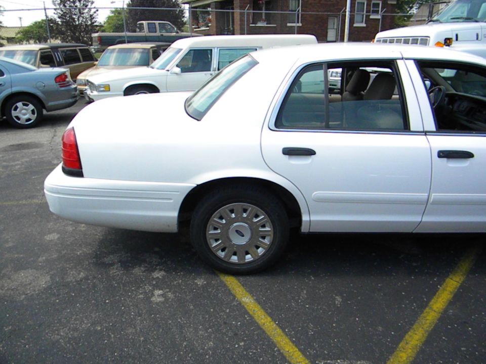 2003 Ford Crown Victoria parked in a lot, side view. Other vehicles are visible in the background