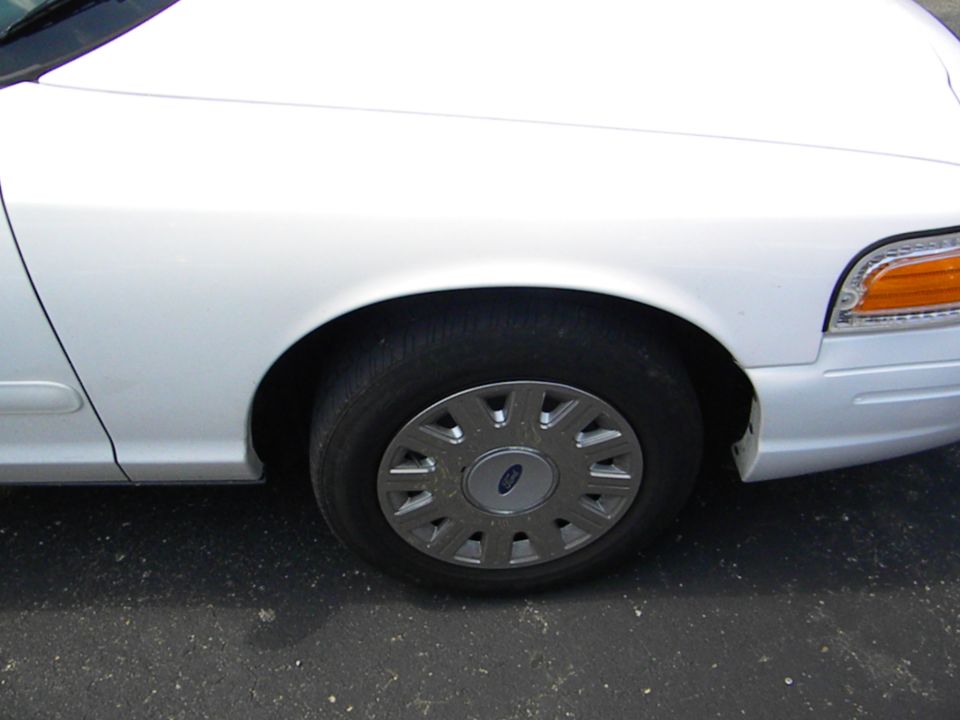 Front wheel and fender of a white 2003 Ford Crown Victoria