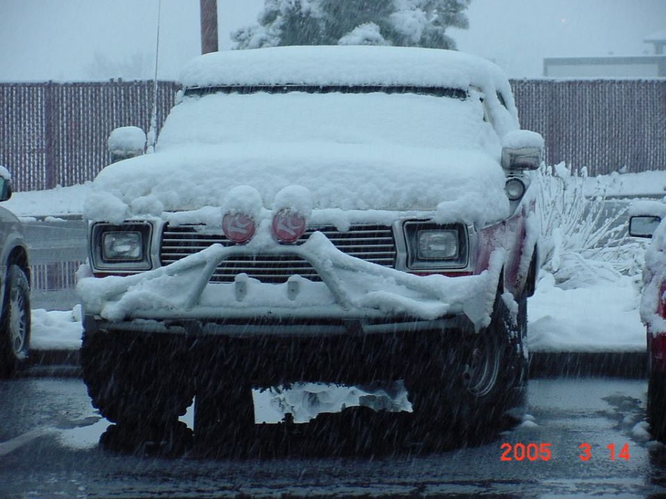 Snow-covered red Bronco front view with brush guard and red-covered auxiliary lights, snowing, dated 2005-3-14