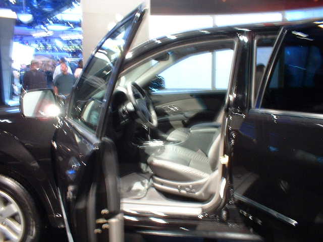 Interior of a black car, driver's seat and door visible. Watermark reads SUPERMOTORS.NET
