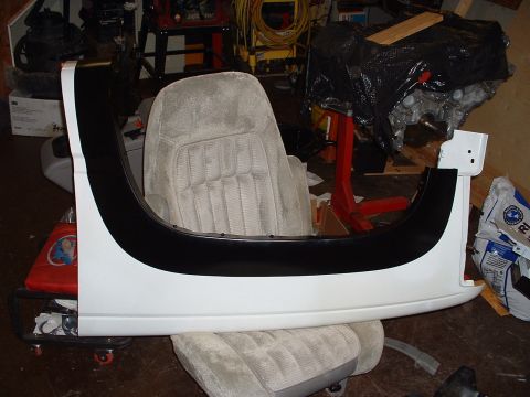 1994 GMC Suburban - A white fender flare with black trim is displayed in front of a vehicle seat, with an engine in the background.