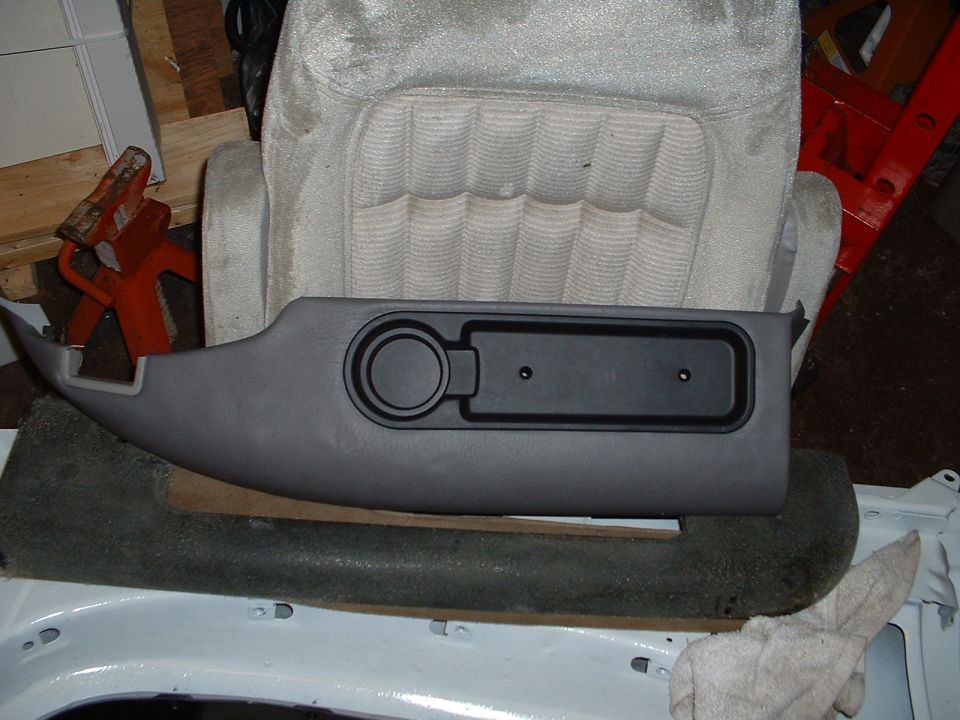 Refinished gray door trim panel with armrest recess propped on carpet in a shop