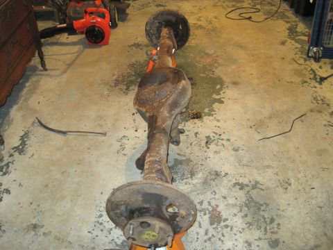 1979 Ford Bronco - A rusty rear axle assembly is displayed on an orange jack stand in a garage setting.